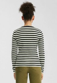 Gestreiftes langärmliges Oberteil in Schwarz und Weiß. Enganliegendes Design mit geripptem Material, Rundhalsausschnitt und einfarbigen Bündchen.