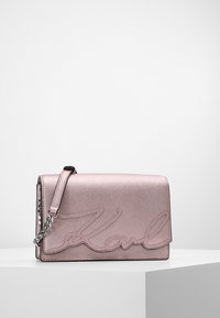 Vaaleanpunainen keinonahkainen käsilaukku, jossa ketjuhihna, kohokuvioitu "Karl"-logo, teksturoitu pinta sekä suorakulmainen muoto läppäkannella.