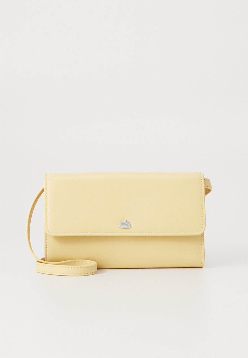Yellow leather crossbody bag with flap closure, silver logo accent, and matching strap. Smooth texture and rectangular shape.