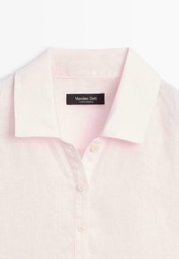 Chemise en lin rose clair avec un col pointu blanc et trois boutons sur le devant, étiquetée Massimo Dutti.