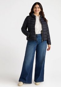 Chaqueta de plumas azul marina con diseño acolchado, frente con cremallera y dos bolsillos laterales, combinada con unos vaqueros de pierna ancha azul claro y zapatillas crema.