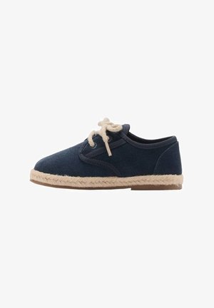 Scarpa di camoscio blu navy con suola in corda beige, caratterizzata da punta arrotondata, design con lacci e una superficie liscia. Stile minimalista con dettagli semplici.