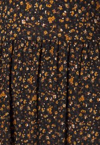 Tissu noir avec un motif floral comprenant des accents jaunes, blancs et verts. Design texturé et plissé avec des couleurs atténuées.