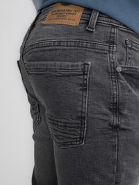 Jeans de mezclilla gris con un acabado texturizado, que cuentan con un parche de cuero en la cintura, múltiples bolsillos y un detalle de costura en contraste.