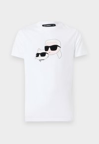 T-shirt bianco in cotone con stampa grafica di un personaggio dei cartoni animati e un gatto, entrambi con occhiali da sole neri, sul davanti.