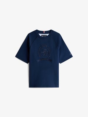 Mørkeblå kortermet T-skjorte med rund hals, med et teksturert våpenmerke og et lite flagglogo på ermet.