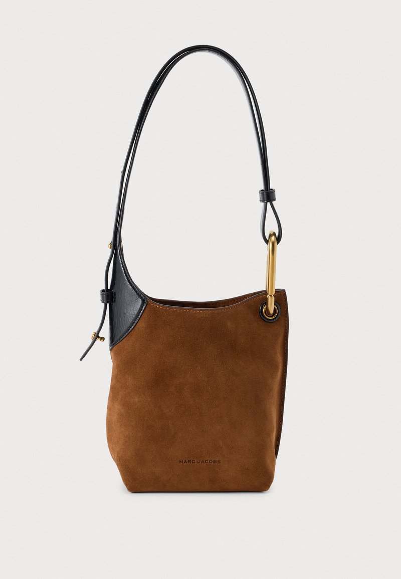Кафява велурена чанта за рамо Marc Jacobs с черни кожени кантове, дълга черна презрамка и златисти метални елементи на изчистен светъл фон.