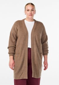 Cardigan lavorato a maglia marrone con scollo a V, apertura frontale, maniche lunghe e due tasche anteriori. La texture è a coste e di peso medio.