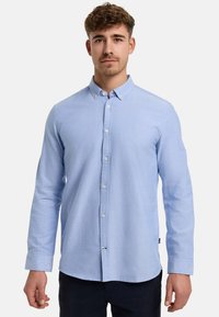 Camicia button-up azzurro chiaro con maniche lunghe, realizzata in un tessuto morbido. Presenta un piccolo logo ricamato sul lato sinistro del petto e un colletto classico.