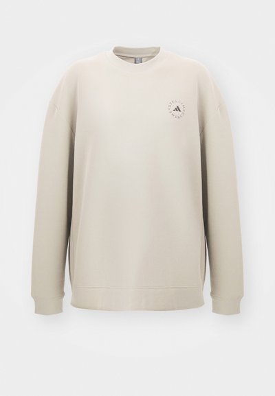 Bežinis džemperis su apvaliu kaklu, ilgomis rankovėmis ir šoninėmis skaidrėmis. Priekyje yra mažas logotipas, atitinkantis kontrastingą spalvą.