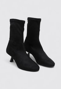 Black ankle boots with a snug fit, made of soft suede. Features a pointed toe and a short, block heel for added elevation.