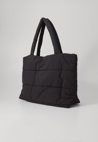 Svart, vadderad tote-väska med två robusta handtag, med en vadderad textur och rektangulär form. Ingen synlig hårdvara eller dekoration.