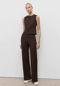 Hnědý výrazným žebrováním třídílný outfit se bezramenným topem a přizpůsobenými kalhotami s vertikálními pruhy. Jednoduchý design a rovný střih.