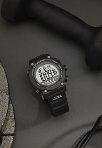 Musta digitaalne kell ümmarguse kellanäidikuga, mis näitab aega, kuupäeva ja ringimälusid; omab kummist rihma ja veekindlust, samuti hõbedasi aktsente.