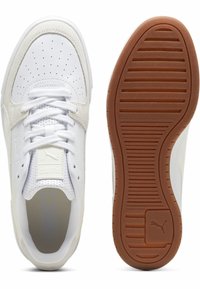 Vita träningsskor med överdel i slätt läder, perforerad tåbox och en tanfärgad gummisula med horisontella räfflor för grepp.