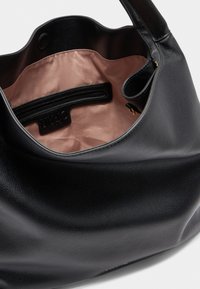 Sac à main en cuir noir avec un extérieur texturé, doublure rose douce, poche intérieure et un design incurvé. Comprend une poignée supérieure pour le transport.