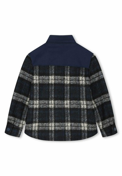 Vue arrière d'une chemise à manches longues avec un empiècement bleu marine et un motif à carreaux noir, blanc et gris sur le bas du dos et les manches.