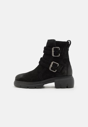Bottines noires en daim, dotées de deux sangles à boucle ajustables, d'une semelle en caoutchouc épaisse et d'une lanière pour un enfilage facile.