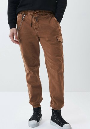 Pantalons cargo marron avec une coupe fuselée, dotés de poches latérales, d'une taille à cordon et de poignets côtelés. Fabriqués en tissu texturé.