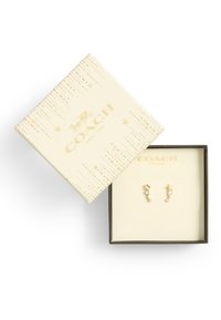 Goudkleurige oorbellen in een geschenkdoos, met ster- en spiraalvormen en heldere crystalaccenten; de doos heeft een gemêleerde crèmekleurige buitenkant en een logo.