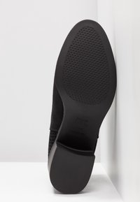 Scarpa in suede nero con suola in gomma testurizzata. Presenta un tacco flat e un design tagliato lungo i lati per favorire la traspirazione.