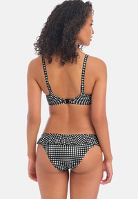 Bikini de cuadros en blanco y negro con tirantes ajustables, cinturilla con volantes en la parte inferior, material suave y un corte deportivo.