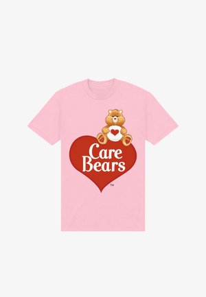 Camiseta rosa con un osito cariñoso marrón sosteniendo un corazón blanco y un gran corazón rojo debajo con el texto "Care Bears" en blanco.