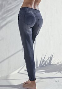 Dunkelgraue Jogginghosen mit einem bequemen elastischen Bund und Bündchen an den Knöcheln, ausgestattet mit Gesäßtaschen und einer weichen Denim-Textur.