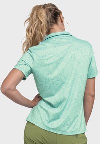 Helles türkisfarbenes Polohemd mit einem dezenten Muster, kurzen Ärmeln und einem Kragen. Weiche Textur, figurbetonte Passform und abgerundeter Saum.