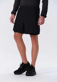 Svarta sportshorts med resårmidja, lättviktigt tyg och en diskret logotyp. Kombinerad med svarta sportskor.