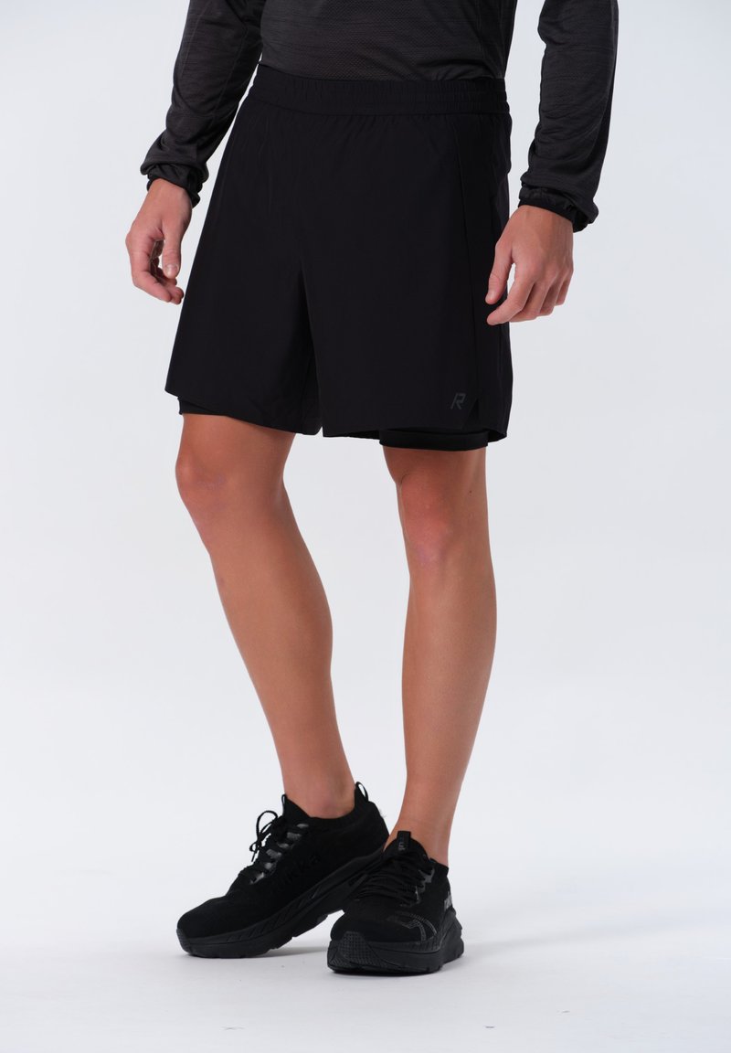 Svarta sportshorts med resårmidja, lättviktigt tyg och en diskret logotyp. Kombinerad med svarta sportskor.