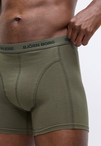Boxer da uomo verde con design a tinta unita, elastico in vita con il logo "BJÖRN BORG" e dettagli cuciti. Tessuto morbido in misto cotone.