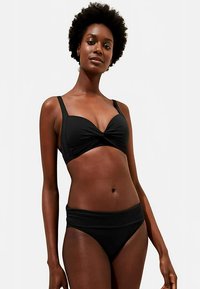 Czarny zestaw bikini z topem zawiązywanym na przodzie z regulowanymi ramiączkami oraz majtkami z wysokim stanem. Gładka, elastyczna tkanina z minimalną ilością szwów.