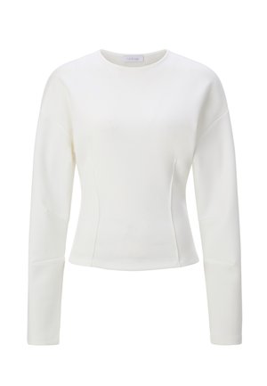 Valge pika varrukaga särk, tehtud siledast kangast, omab ümmargust kaelust, keha järgivat lõiget ja varrukatel õmbluste detaili.