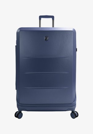 Blauwe hard-shell koffer met een glanzende afwerking, verticale groeven, uitschuifbare handgreep en vier zwarte wielen voor mobiliteit.