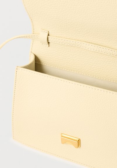 Δερμάτινη τσάντα χιαστί σε κρεμ χρώμα με ανοιχτό καπάκι, χρυσό ορθογώνιο κούμπωμα και ορατά εσωτερικά ράμματα και θηλιά για λουρί.