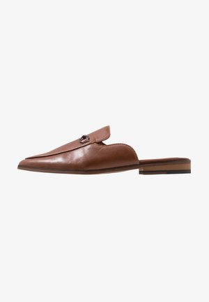 Mule marron en cuir à enfiler avec bout pointu, boucle métallique décorative, petit talon en bois empilé et arrière ouvert.