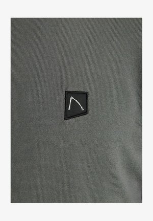 Tela de punto gris con un pequeño parche negro que presenta un diseño abstracto en blanco. La textura es suave y uniforme en toda su extensión.