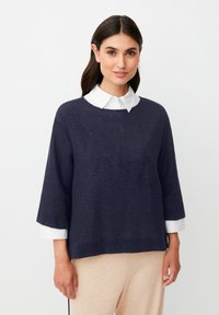 Pullover navy blue a maglia con una vestibilità ampia, caratterizzato da maniche a 3/4 e un colletto bianco. La texture appare morbida e leggermente strutturata.