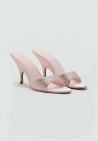 Sandales à talons ouverts en rose doux avec une texture métallique tissée, présentant une large bride avant et un talon fin. Semelle intérieure lisse.