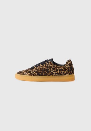 Low-top sneaker met luipaardprint bovenkant, zwarte veters en lichtbruine rubberen zool op een effen lichtgrijze achtergrond.