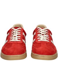 Baskets en daim rouge avec des lacets blancs et des rayures sur les côtes. Pointe arrondie, profil bas et une semelle en caoutchouc texturé beige.