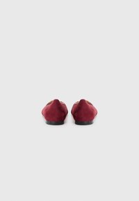 Balerini din nubuc roșu cu toc mic din cauciuc negru și accente decorative aurii în partea de sus. Textură netedă și design cu vârful rotund.