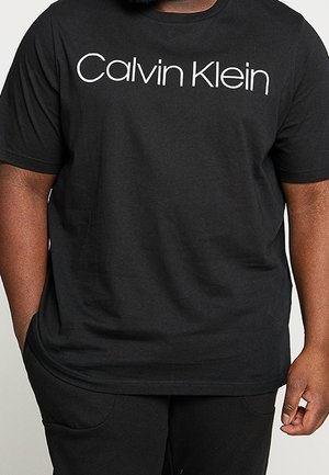 Černé bavlněné tričko s bílým logem "Calvin Klein" přes hrudník, krátké rukávy a volný střih. Bezešvý výstřih a manžety.