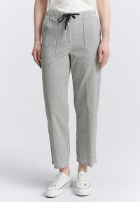 Pantalons en coton rayés avec une taille élastique et un cordon de serrage, dotés de poches avant et d'une coupe décontractée. Portés avec des baskets blanches.