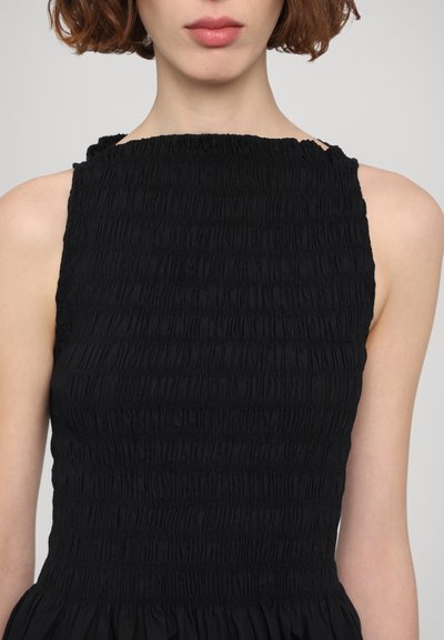 Black dress featuring a smocked bodice with a high neckline and wide straps. The fabric has a textured, gathered appearance.