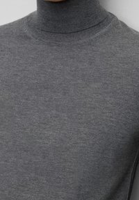 Pull gris à col roulé en tricot doux. Présente une coupe ajustée avec un col haut et des finitions côtelées.