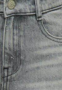 Šviesiai pilki džinsai iš džinsinio audinio su subtiliu akmens skalbimo efektu, papuošti mažais sidabro spalvos metaliniais akcentais ir penkių kišenių dizainu.