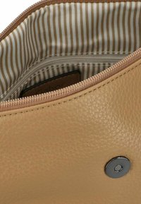 Tasche aus braunem Leder mit gestreiftem Futter, Reißverschlussverschluss und einem runden, metallenen Druckknopf-Detail. Texturierte Oberfläche sichtbar.