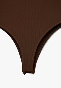 Brązowe bikini dolne wykonane z teksturowanej tkaniny, charakteryzujące się wysokim krojem i bezszwowymi krawędziami dla gładkiego wykończenia.